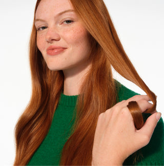 Woman with long red hair being styled on a white background